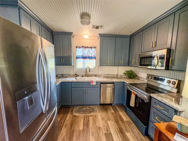 a kitchen with granite countertop a refrigerator stove top oven and sink