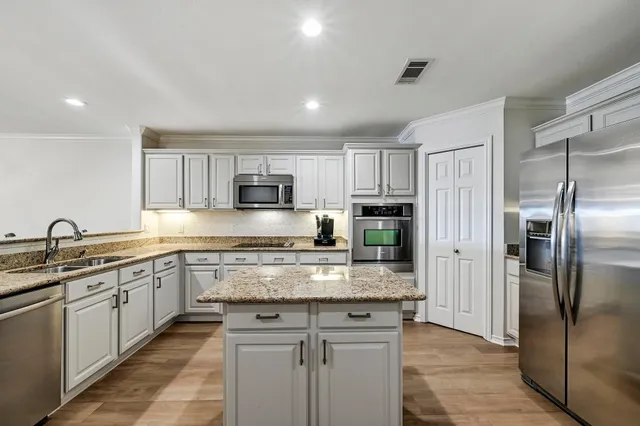 a kitchen with stainless steel appliances granite countertop a refrigerator a sink a stove a microwave and island