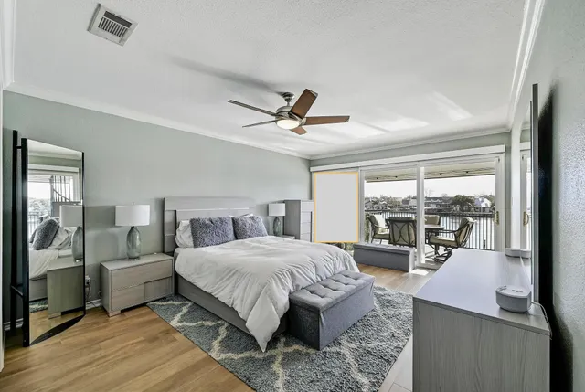 a bedroom with a bed a chandelier and a large window with wooden floor