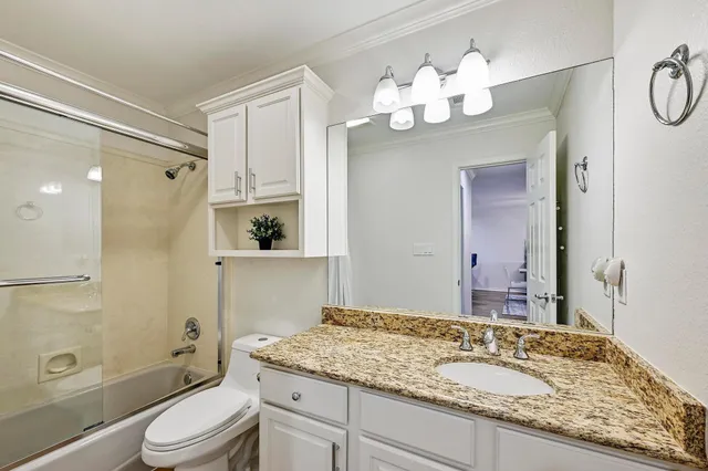 a bathroom with a granite countertop sink a toilet and shower