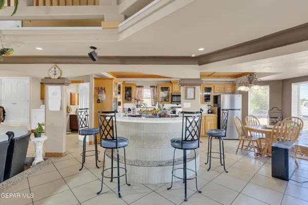 a kitchen with stainless steel appliances kitchen island granite countertop a table chairs and a refrigerator