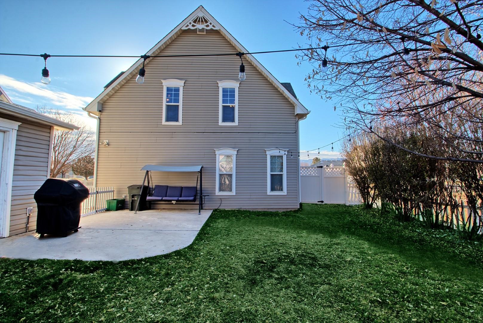 1209 Windsor Park Drive Fruita, CO 81521 - Photo 16 of 26 a view of a white house next to a yard with potted plants and large tree
