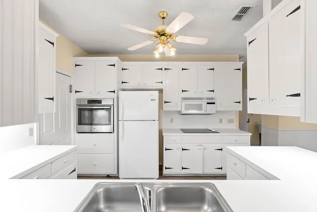 a kitchen with kitchen island white cabinets and refrigerator