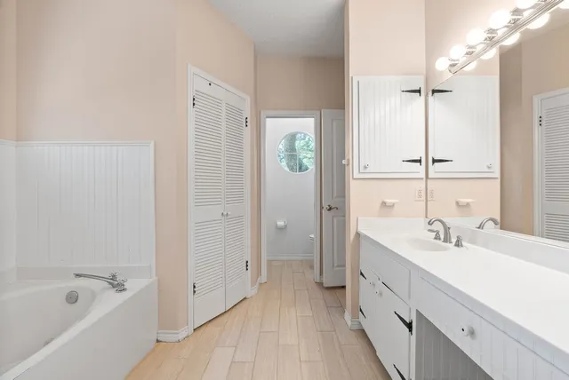 a bathroom with a double vanity sink a mirror and a bathtub