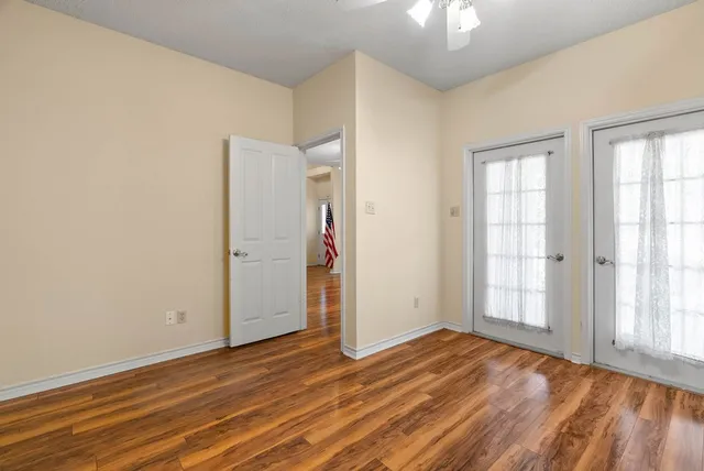 an empty room with wooden floor cabinet and windows