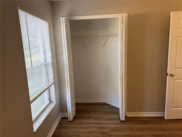 a view of an empty room with wooden floor and entrance