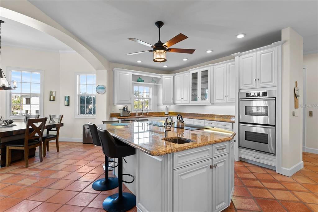 63 Palm Drive Placida, FL 33946 - Photo 10 of 54 a kitchen with stainless steel appliances granite countertop a sink a stove a dining table and chairs with wooden floor