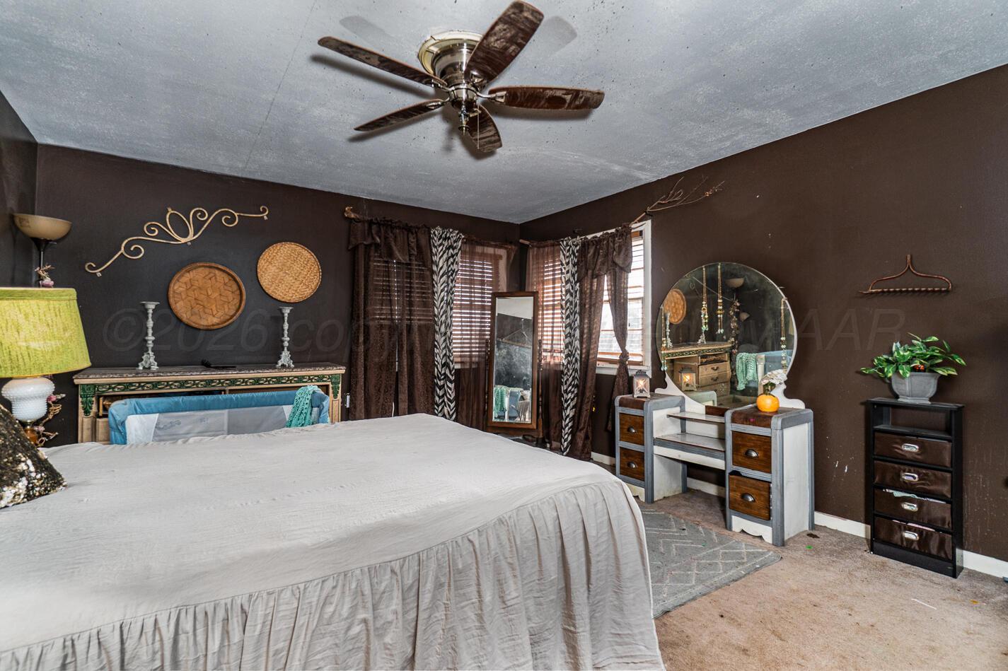 11 Travis Circle Tulia, TX 79088 - Photo 15 of 21 a bedroom with a bed a chandelier and dresser