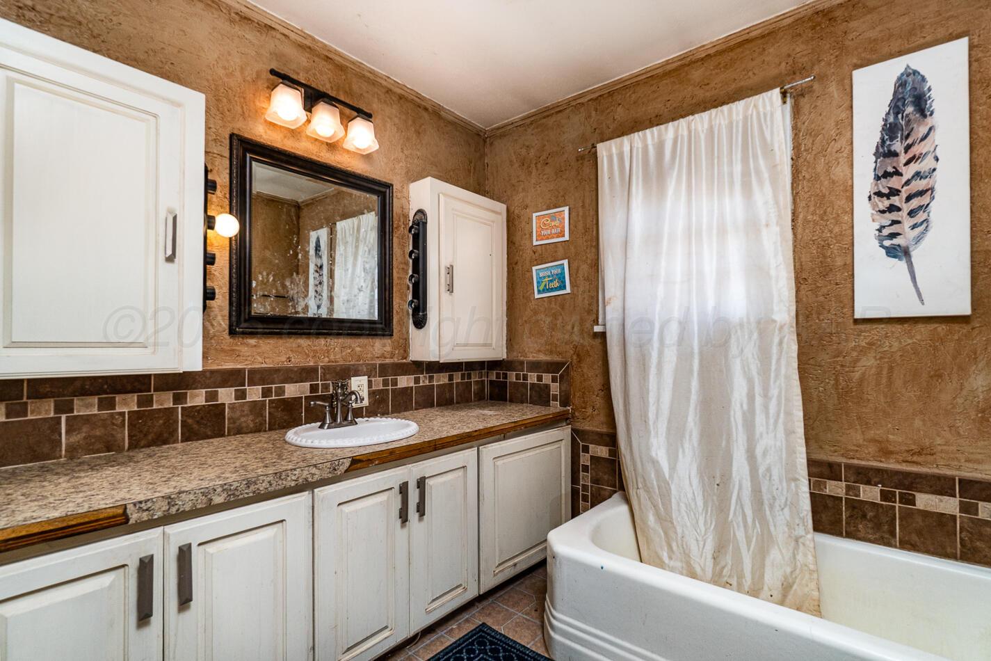 11 Travis Circle Tulia, TX 79088 - Photo 17 of 21 a bathroom with a granite countertop sink and a mirror