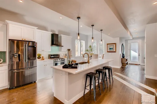 a kitchen with stainless steel appliances a refrigerator a stove a sink dishwasher and white cabinets with wooden floor