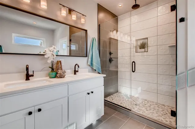 a bathroom with a granite countertop sink a mirror and shower