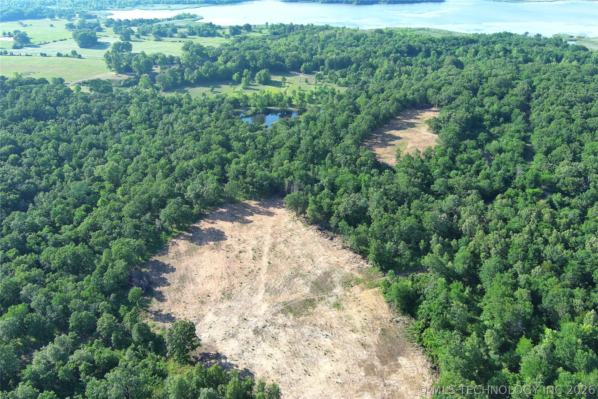 20862 East 1160th Road Keota, OK 74941 - Photo 6 of 47 Expansive wooded acreage featuring a cleared building site, a tranquil pond, and a distant body of water