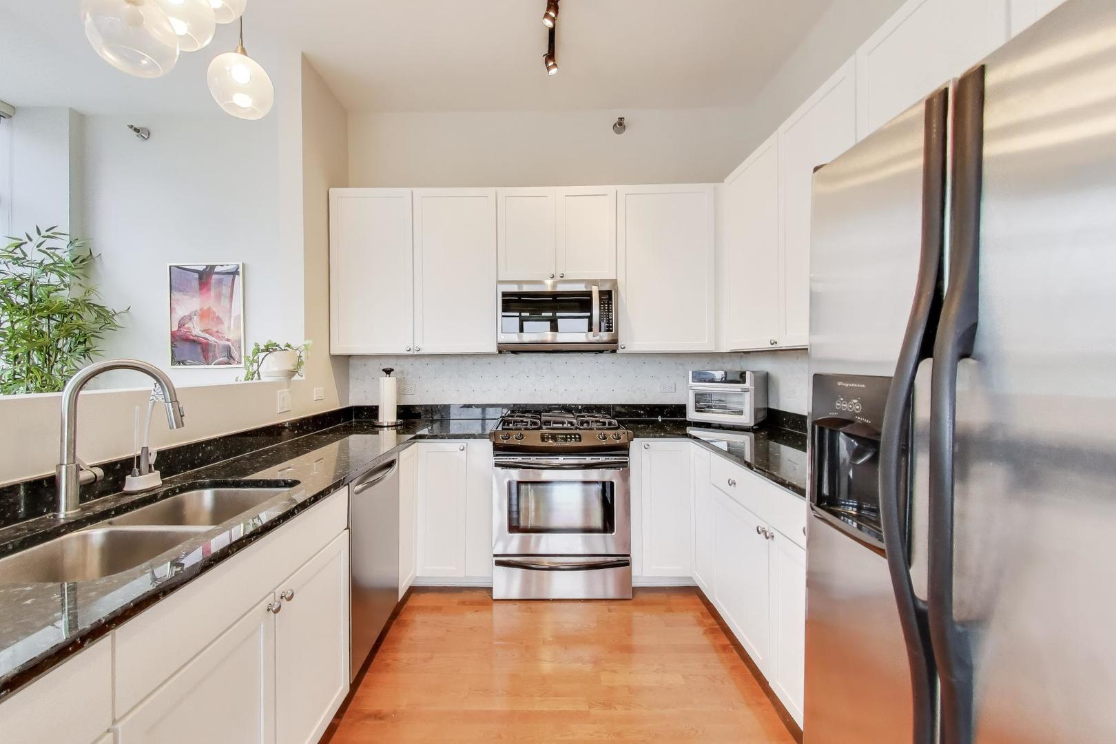 901 West Madison Street, Unit 710 Chicago, IL 60607 - Photo 5 of 35 a kitchen with granite countertop a stove a sink and a refrigerator