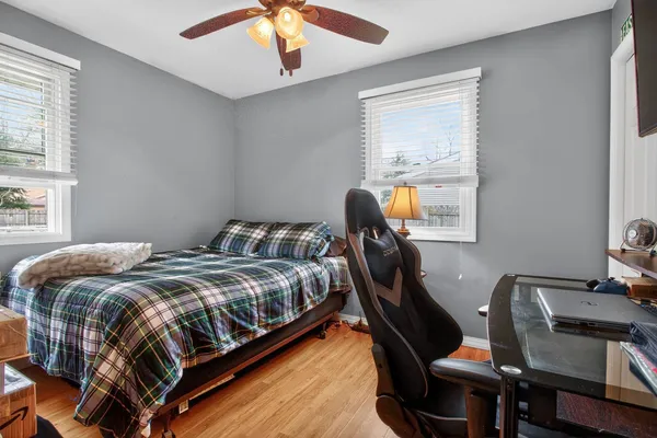a bedroom with a bed a desk and chair with windows