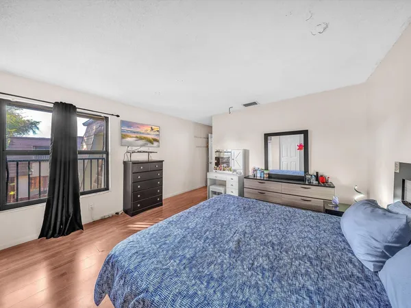 a bedroom with a bed dresser and a large window