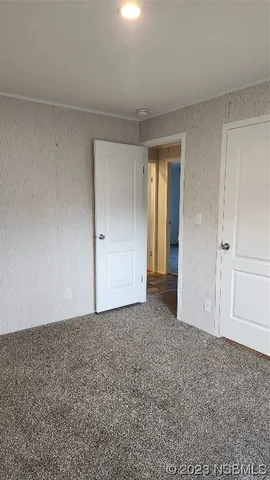 a view of a refrigerator in kitchen and an empty room