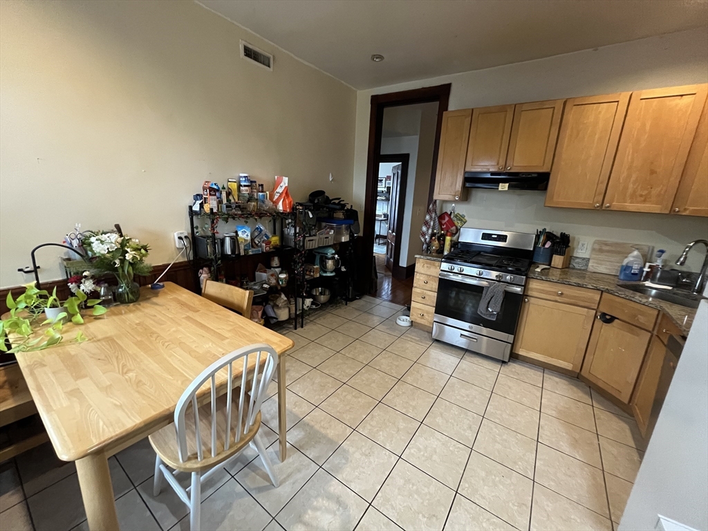 142 St Alphonsus Street, Unit 3 Boston, MA 02120 - Photo 5 of 13 a kitchen with stainless steel appliances kitchen island granite countertop a table chairs sink and cabinets