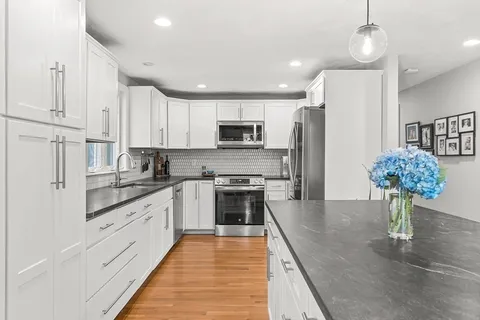 a large kitchen with stainless steel appliances granite countertop a stove a sink and a refrigerator