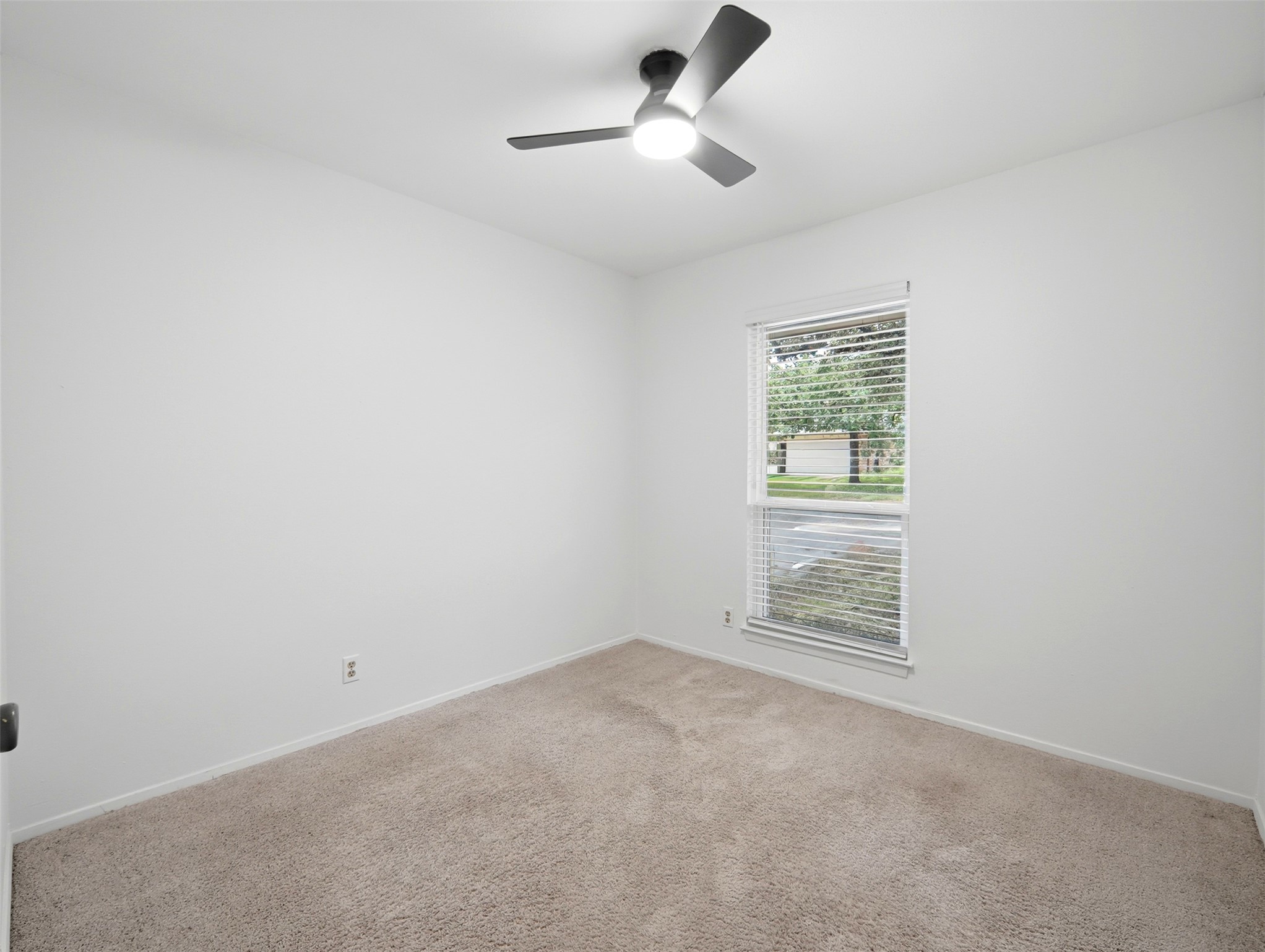 7001 Windrift Way Austin, TX 78745 - Photo 15 of 17 A well-proportioned room with soft carpeting and a window overlooking a green outdoor space.
