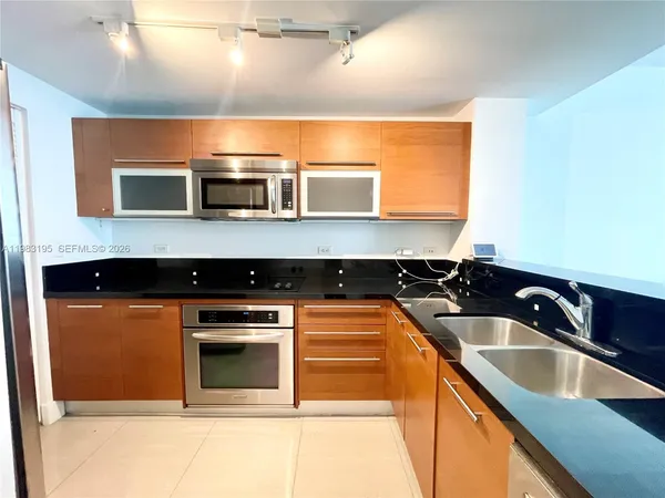 a bedroom with a bed lamp on desk and a window