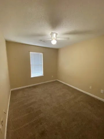 an empty room with a window and a ceiling fan