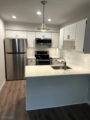 a kitchen with stainless steel appliances a refrigerator a stove a sink and white cabinets