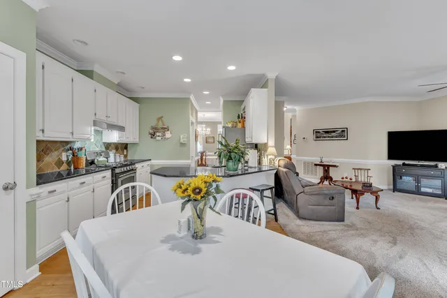 a kitchen with stainless steel appliances granite countertop a table and chairs in it