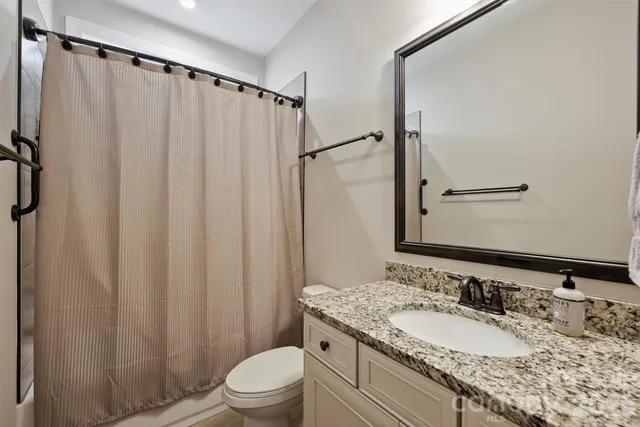 a bathroom with a granite countertop sink toilet and a mirror