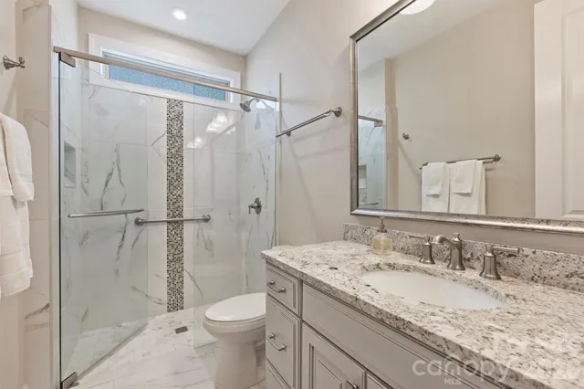 a bathroom with a granite countertop sink toilet and shower