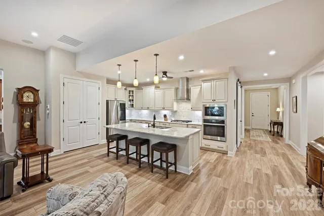 a living room with stainless steel appliances kitchen island granite countertop furniture wooden floor and a view of kitchen