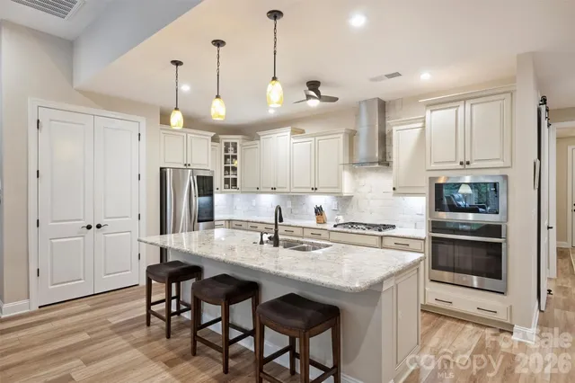 a kitchen with stainless steel appliances granite countertop a sink a stove a refrigerator and island with wooden floor