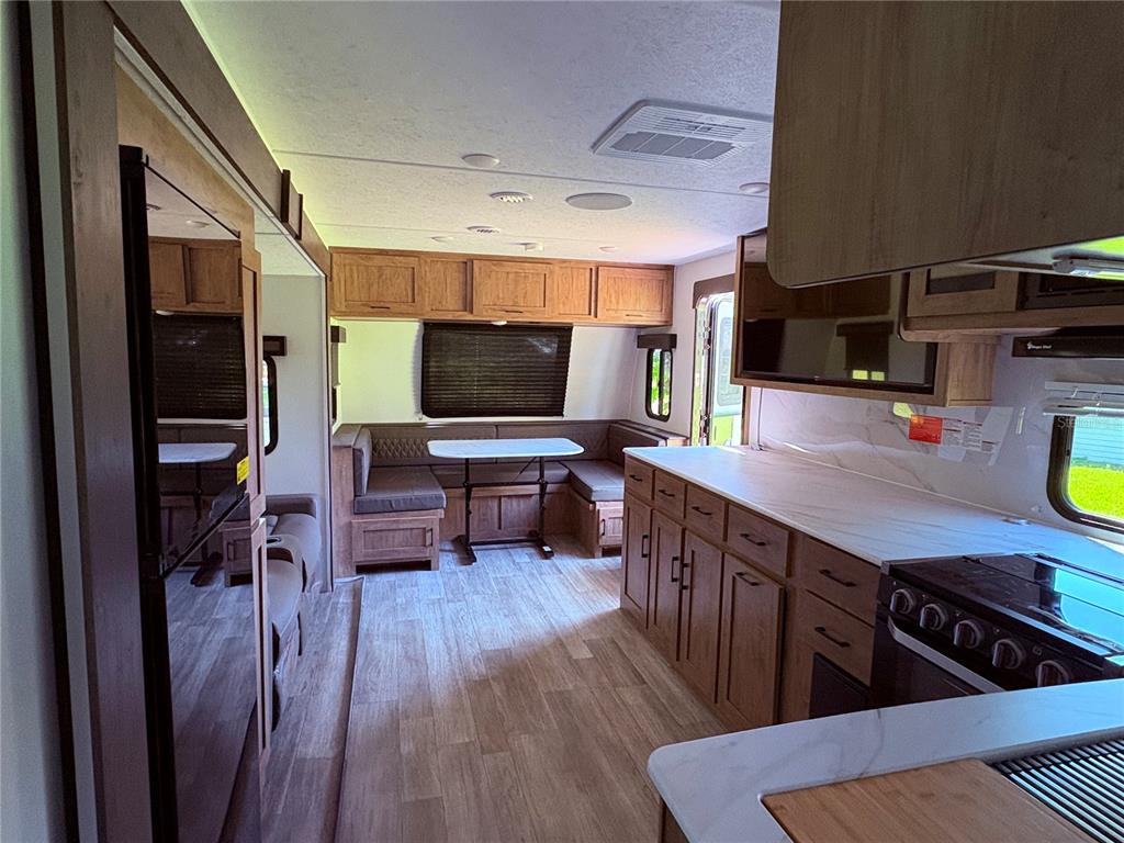 1575 Northeast 100th Street Anthony, FL 32617 - Photo 27 of 29 a kitchen with stainless steel appliances a kitchen island hardwood floor sink stove dining table and chairs