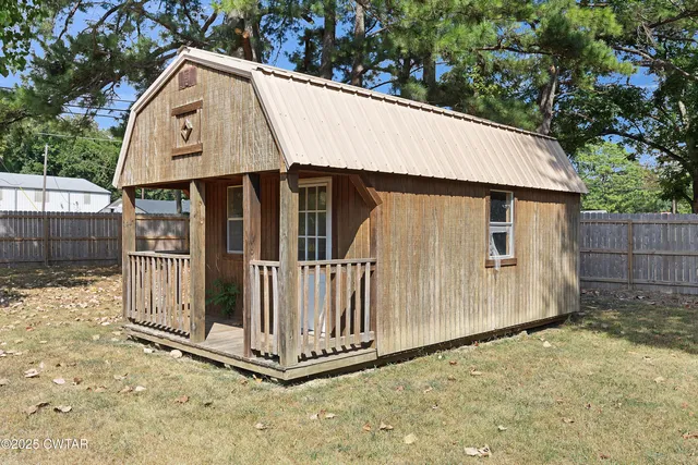 a view of a small house with wooden fence