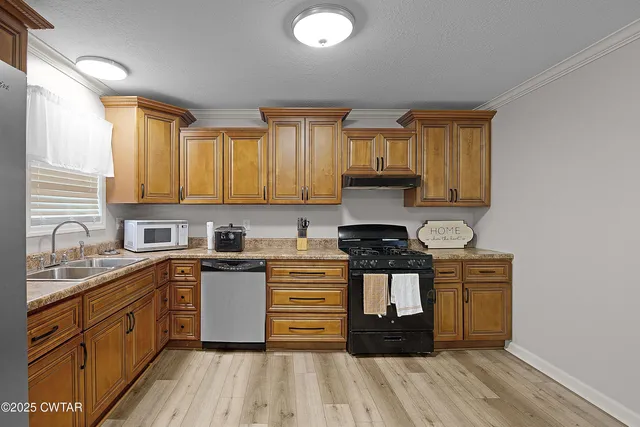 a kitchen with stainless steel appliances granite countertop a stove a sink dishwasher and a microwave oven with wooden cabinets