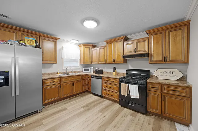a kitchen with granite countertop a refrigerator stove top oven and sink