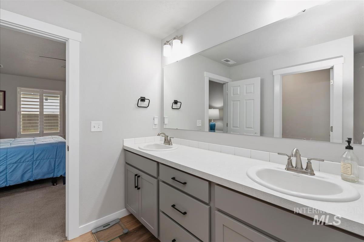 15451 Lutsen Avenue Caldwell, ID 83607 - Photo 26 of 39 Bathroom vanity featuring a single basin sink with a brushed nickel faucet, light-toned countertop, and a full-width mirror