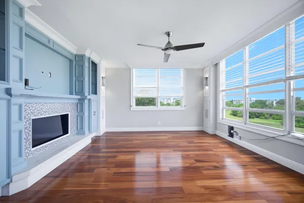 a view of empty room with wooden floor fan and windows
