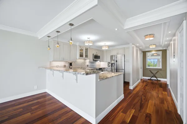 a view of a kitchen with kitchen island wooden floors granite counter tops and a view of living room