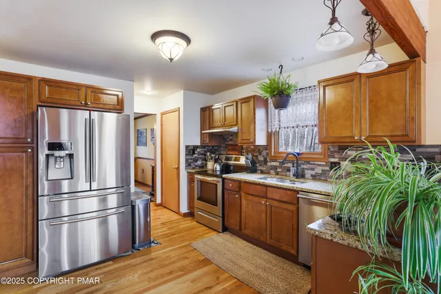 a kitchen with stainless steel appliances granite countertop a refrigerator a stove a sink dishwasher and a refrigerator