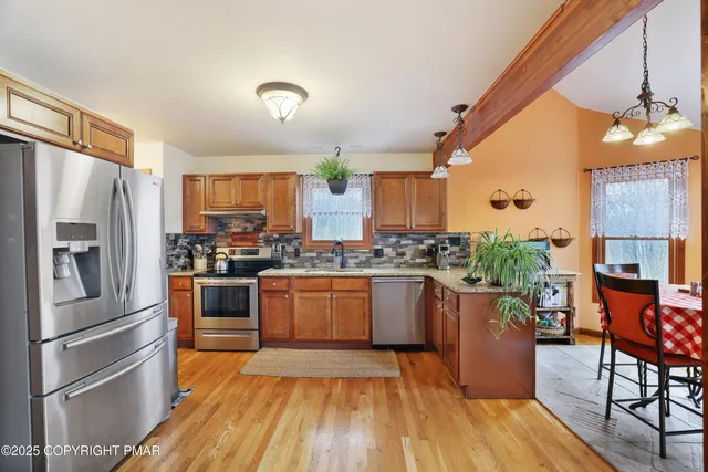 a kitchen with stainless steel appliances granite countertop a refrigerator a stove and a wooden floors