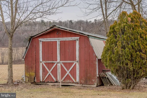 a view of wooden house with large trees and wooden fence