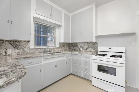 a kitchen with granite countertop white cabinets and white appliances