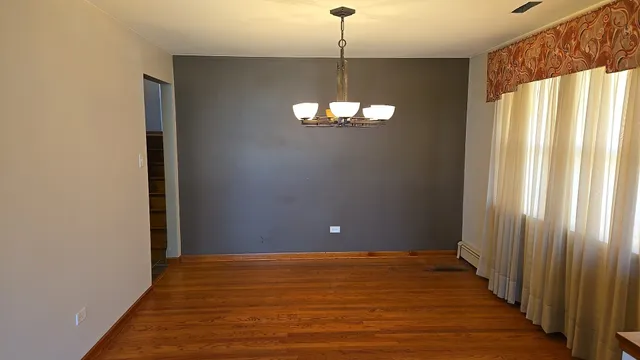 a view of a livingroom with a chandelier wooden floor and a chandelier