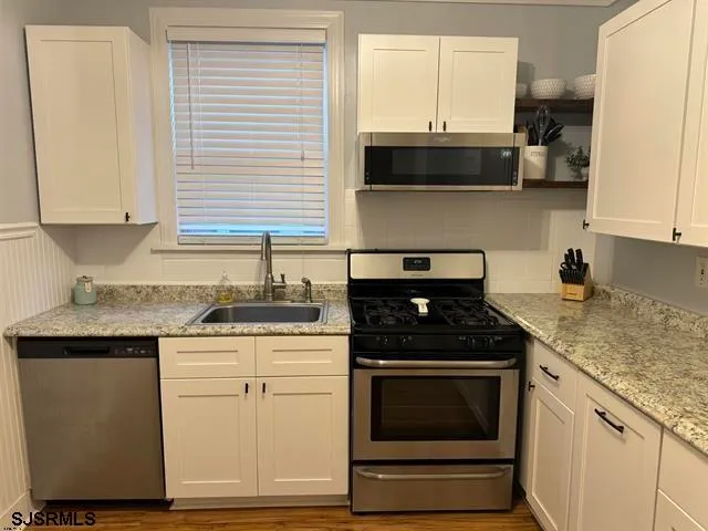 a kitchen with granite countertop white cabinets stainless steel appliances and a sink