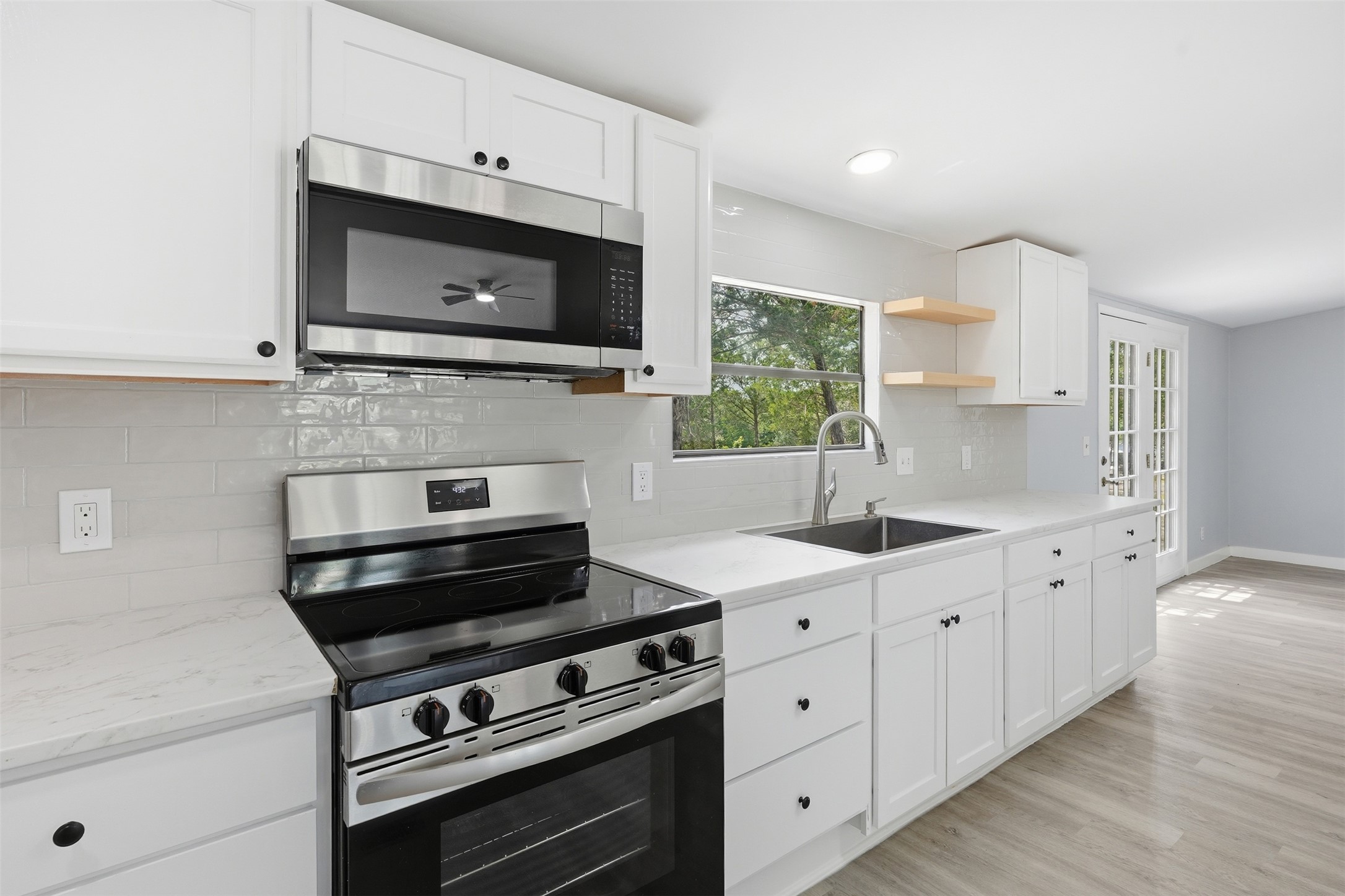 154 Antioch Road Smithville, TX 78957 - Photo 12 of 32 A well-lit kitchen with sleek white cabinetry, stainless steel appliances, and a refreshing view of nature.