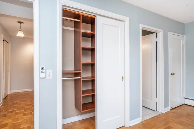 a view of a hallway with wooden floor and closet
