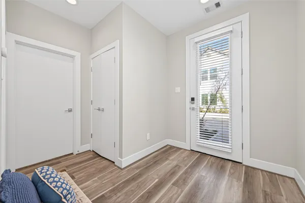 an empty room with wooden floor closet and windows