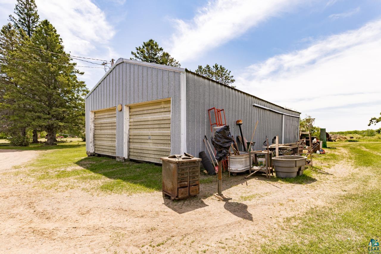 6606 Metso Road Kettle River, MN 55757 - Photo 76 of 84 Corrugated metal garage with two roll-up doors, a side sliding door, and a gravel approach