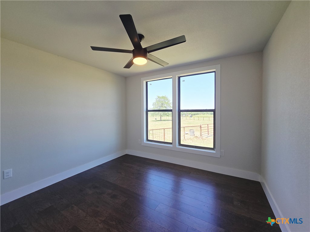 930 Elm Creek Road Rockdale, TX 76567 - Photo 10 of 25 an empty room with wooden floor ceiling fan and windows
