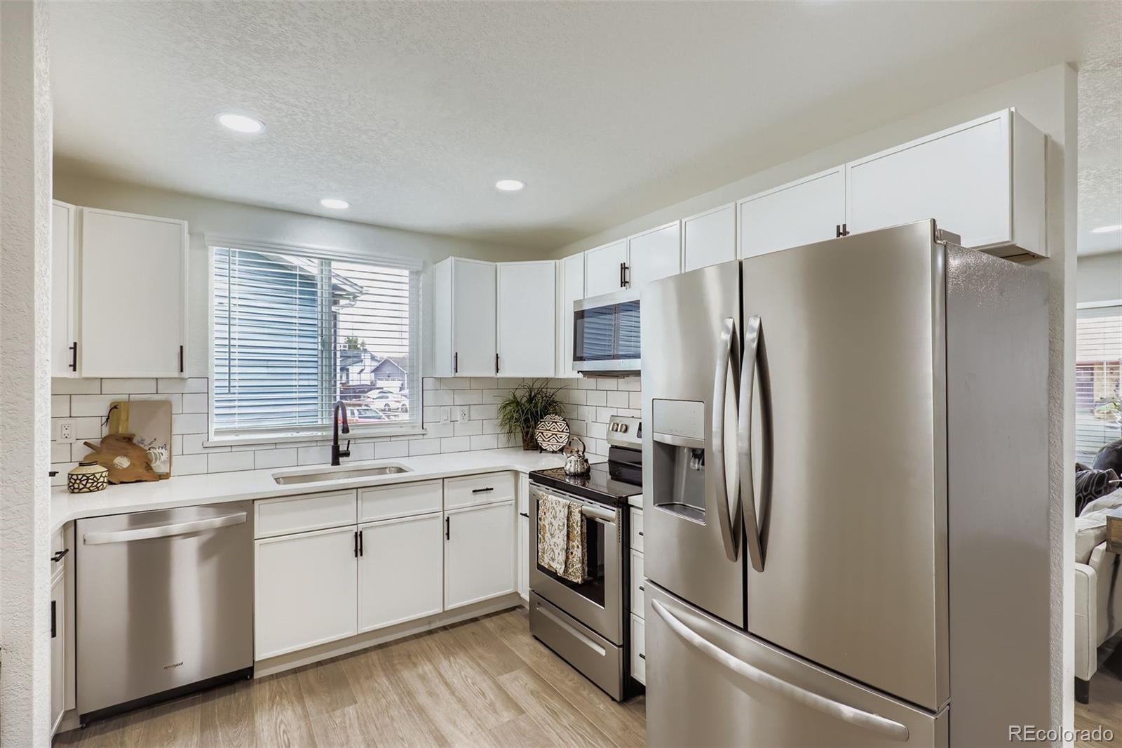 4465 Durham Court Denver, CO 80239 - Photo 11 of 28 a kitchen with white cabinets white stainless steel appliances and sink